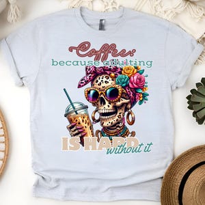 Könnte beinhalten: Ein hellgraues T-Shirt mit einem bunten Motiv eines Schädels, der eine Sonnenbrille und ein Blumenband trägt. Der Schädel hält eine Tasse Kaffee und der Text "Coffee because adulting is hard without it" ist unter dem Motiv gedruckt.
