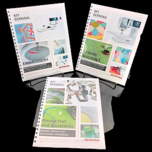 Può includere: Tre quaderni a spirale con copertine colorate che mostrano macchine da cucire e disegni di ricamo. I titoli sono "My Bernina Ricamo", "My Bernina Macchine da Cucire" e "My Bernina Piedini e Accessori".