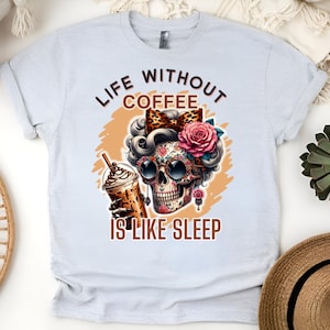 Op de afbeelding: Een lichtgrijs T-shirt met een afbeelding van een suikerschedel met een koffiebeker en de tekst "Life Without Coffee Is Like Sleep".