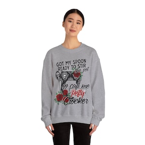 May include: Gray sweatshirt with a graphic of a vintage-style kitchen mixer with red roses and the text "Got my spoon ready to stir the pot so call me Petty Crocker".