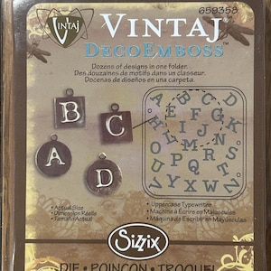 May include: A vintage-style alphabet die set for use with an embossing machine. The die set includes uppercase letters A through Z. The packaging is brown with a gold border and features the text "VintaJ DecoEmboss" and "Sizzix".