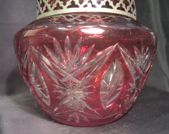 May include: A ruby red glass bowl with a cut crystal design. The bowl has a silver-toned metal rim.
