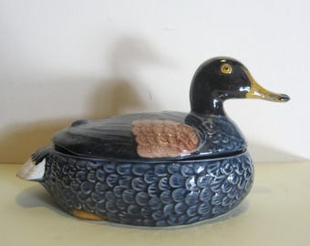 Könnte beinhalten: Eine blaue und braune Keramik-Entenschale mit Deckel. Die Ente hat einen gelben Schnabel und einen schwarzen Kopf.