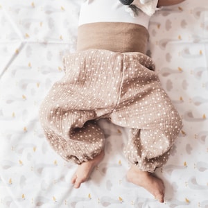 Könnte beinhalten: Eine braune Babyhose mit weißen Punkten. Die Hose ist aus einem weichen, bequemen Stoff und hat eine lockere, fließende Passform.