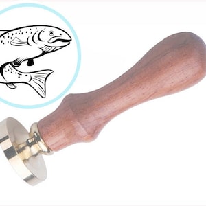 Op de afbeelding: Een lakstempel met een houten handvat en een messing zegel. De zegel heeft een zwart-wit illustratie van een vis in een lichtblauwe cirkel. De handgreep is van een bruine kleur.