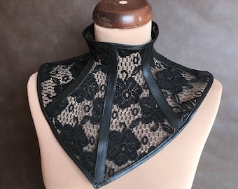 May include: Black lace choker with leather accents. The choker is triangular in shape and has a delicate floral pattern.
