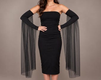 May include: A black strapless midi dress featuring matching detachable arm sleeves. The sleeves are constructed from a solid black fabric on the upper arm and transition into long, flowing, sheer black tulle panels that extend to the floor.