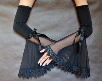 May include: A pair of black elbow-length gloves with lace trim and satin bows. One glove is sheer and the other is opaque.