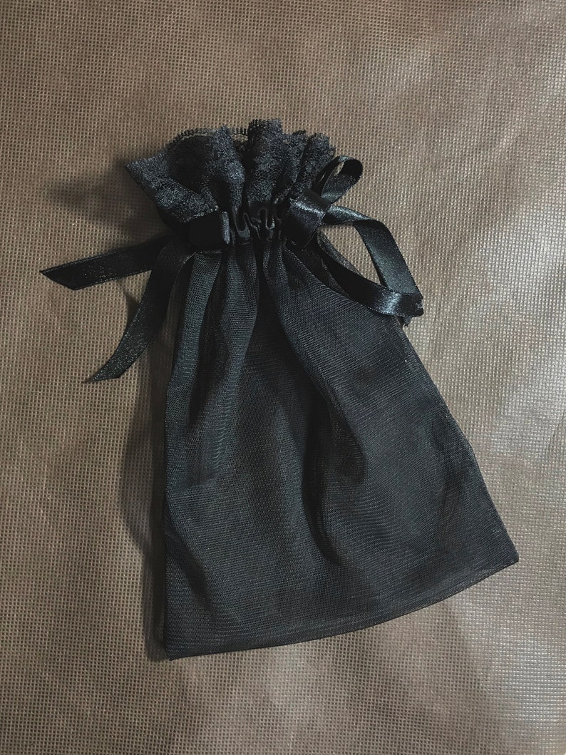 May include: A black mesh drawstring bag with a black ribbon and lace trim.