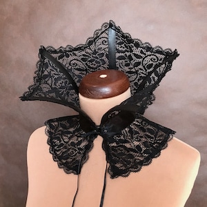 May include: A black lace collar with a scalloped edge. The collar is tied at the front with a black ribbon.