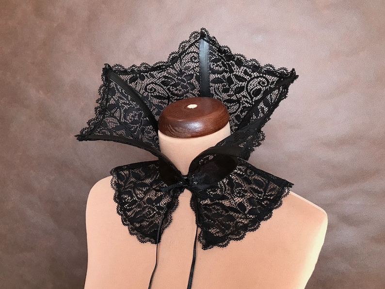 May include: A black lace collar with a scalloped edge. The collar is tied at the front with a black ribbon.