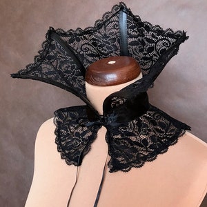 May include: A black lace collar with a satin ribbon tie. The collar has a wide, pointed design and is made of delicate lace.