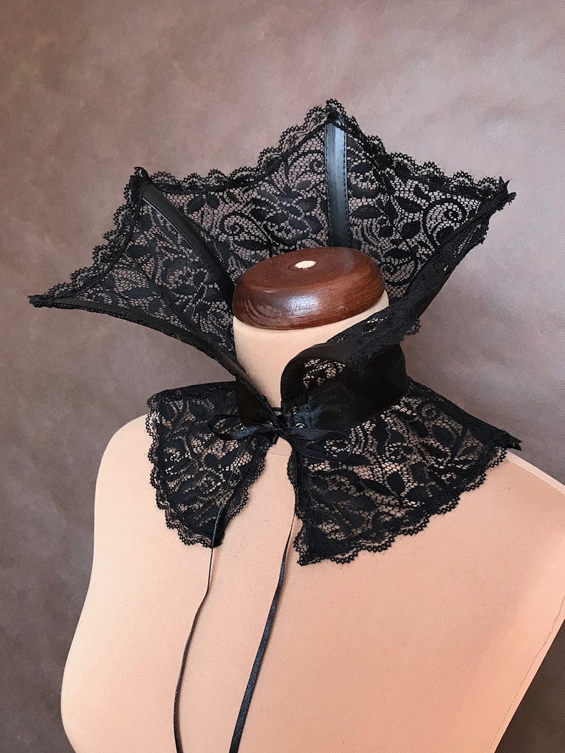 May include: A black lace collar with a satin ribbon tie. The collar has a wide, pointed design and is made of delicate lace.