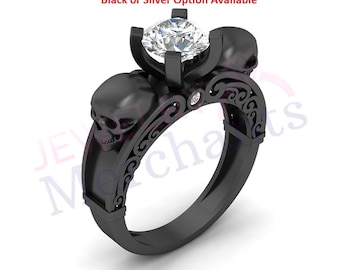 May include: Black ring featuring a large, clear gemstone and three skull accents. The ring has a decorative filigree design on the band. The text "Black or Silver Option Available" is visible in the image.
