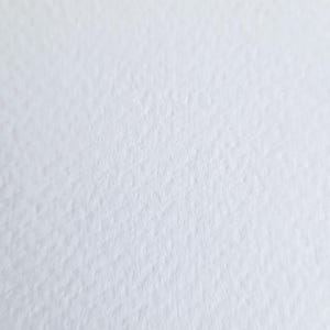 May include: Close-up of a textured, white paper surface. The paper has a slightly rough, uneven texture, creating subtle shadows and variations in tone. The overall appearance is clean and minimalist.