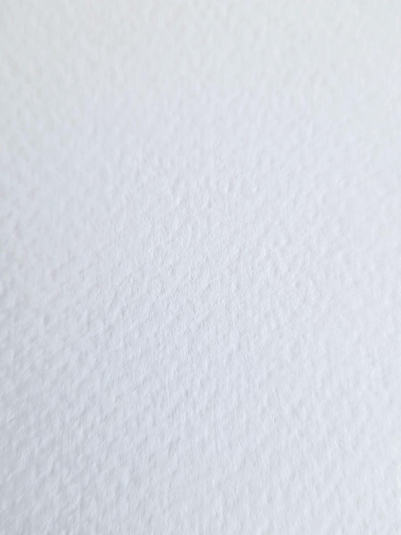 May include: Close-up of a textured, white paper surface. The paper has a slightly rough, uneven texture, creating subtle shadows and variations in tone. The overall appearance is clean and minimalist.