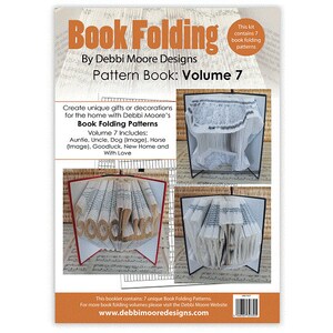 May include: A pattern book titled "Book Folding: Volume 7" by Debbi Moore Designs. The cover features examples of folded book art, including the word "Goodluck." The kit contains seven book folding patterns. The website www.debbiemooredesigns.com is also visible.