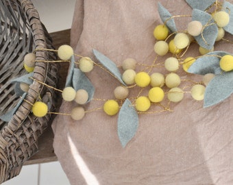 Leaf garland and balls of pale yellow and lemon yellow felt for home decoration