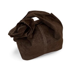 K&ouml;nnte beinhalten: Eine dunkelbraune Hobo-Tasche aus Wildleder mit einer weichen, lockeren Silhouette. Die Tasche verf&uuml;gt &uuml;ber einen einzelnen integrierten Griff, eine vertikale Mittelnaht und eine matte, strukturierte Oberfl&auml;che. Das Design ist unstrukturiert.