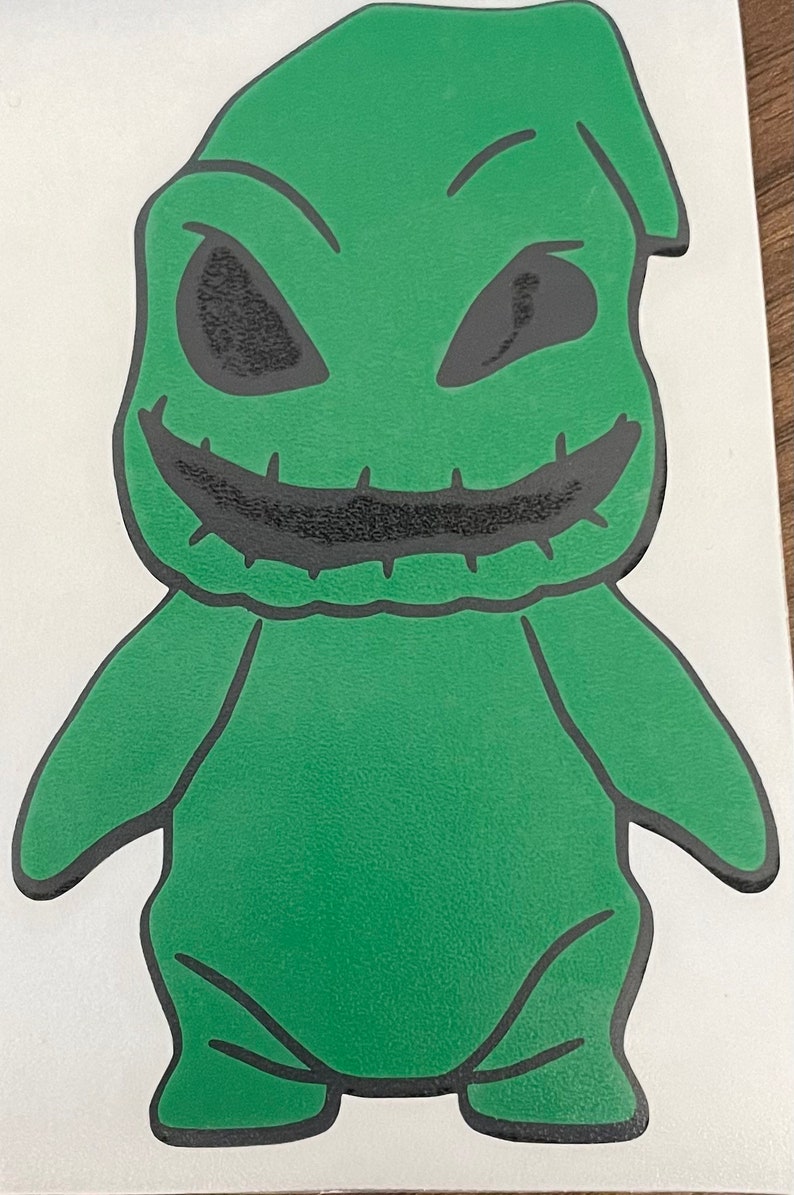 Pode incluir: Personagem de desenho animado verde com uma boca costurada e olhos pretos. O personagem est&aacute; de p&eacute; com os bra&ccedil;os ao lado do corpo.