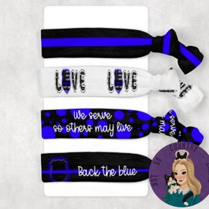 May include: Set of four blue and black hair ties with different designs. The hair ties feature the text "We serve so others may live", "Back the blue", and "Love" with a thin blue line.