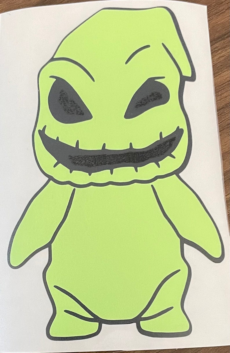 Pode incluir: Um personagem de desenho animado verde com a boca costurada e olhos pretos. O personagem est&aacute; de p&eacute; com os bra&ccedil;os ao lado do corpo.