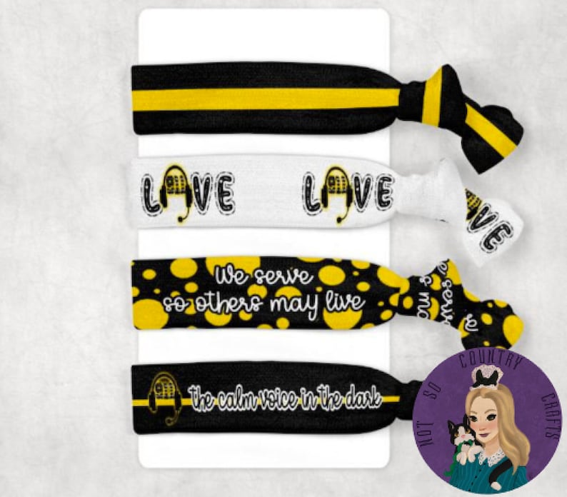 May include: Set of four black and yellow hair ties with different designs. The first hair tie is black and yellow stripes. The second hair tie is white with the word "LOVE" and a black and yellow headset. The third hair tie is black with yellow polka dots and the text "We serve so others may live". The fourth hair tie is black with the text "the calm voice in the dark" and a black and yellow headset.