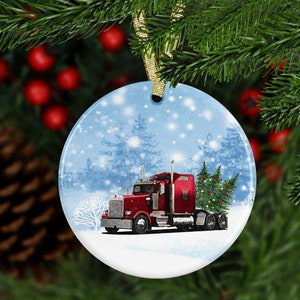 Pu&ograve; includere: Un camion rosso con rimorchio che trasporta un albero di Natale attraverso un paesaggio invernale innevato. Il camion &egrave; decorato con luci e l'albero &egrave; adornato con decorazioni. Questo &egrave; un ornamento rotondo in ceramica.