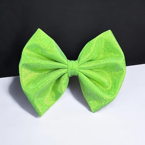 May include: A large, bright green bow made of sparkly fabric. The bow is tied in a classic shape with two loops and a centre knot.