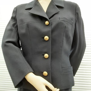 May include: A black blazer with a notched collar and five gold buttons. The blazer has a single pocket on the right side.