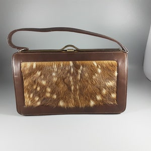 May include: A brown leather handbag with a flap closure and a top handle. The flap is made of a brown and white spotted fur.