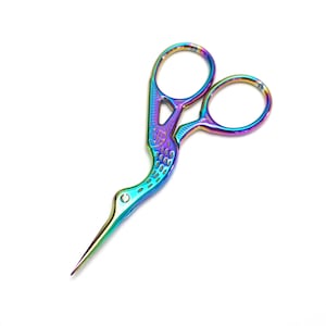 May include: Rainbow iridescent metal scissors with a bird-shaped handle. The scissors have a pointed tip and are designed for detail work.