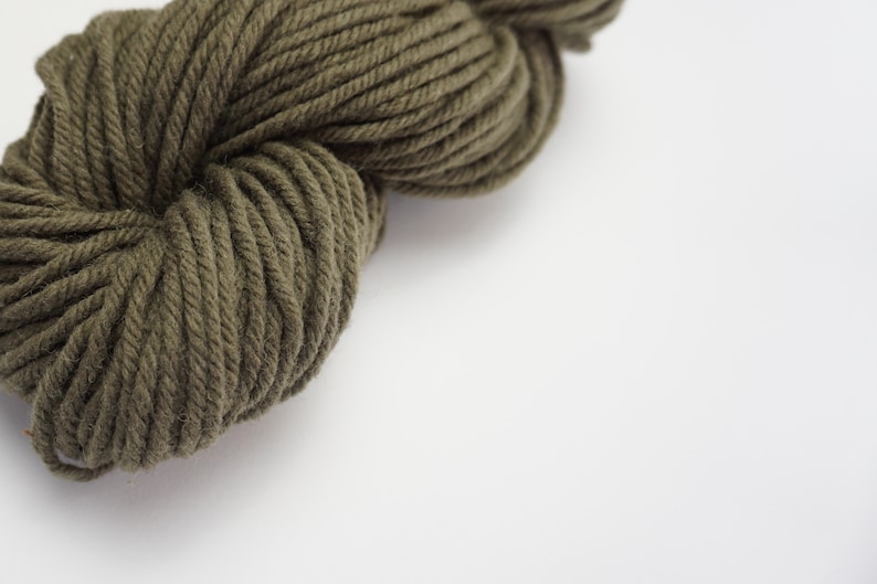 Puede incluir: Un ovillo de hilo de color verde oscuro, un material suave y esponjoso para tejer o hacer ganchillo.