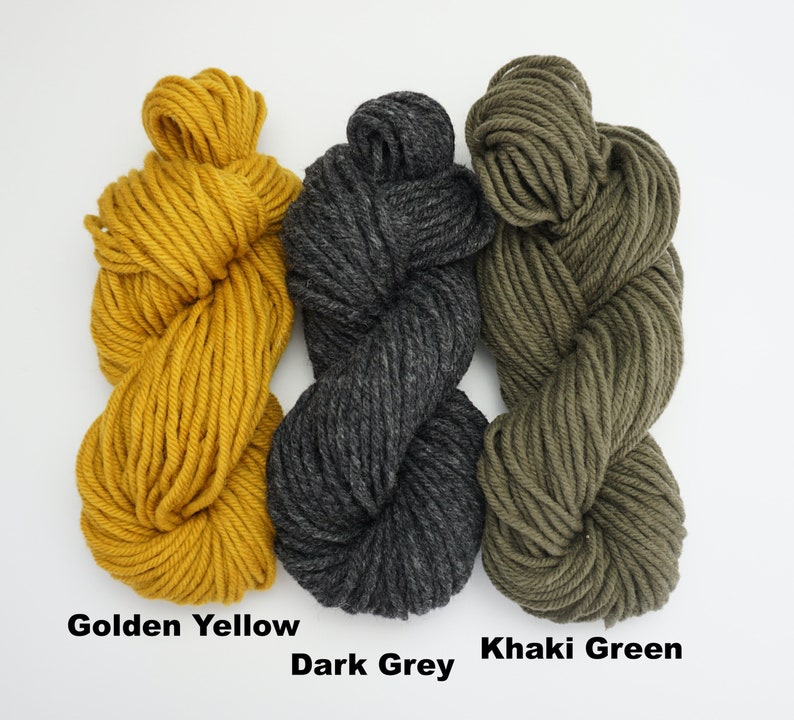 Puede incluir: Tres ovillos de hilo en amarillo dorado, gris oscuro y verde caqui.