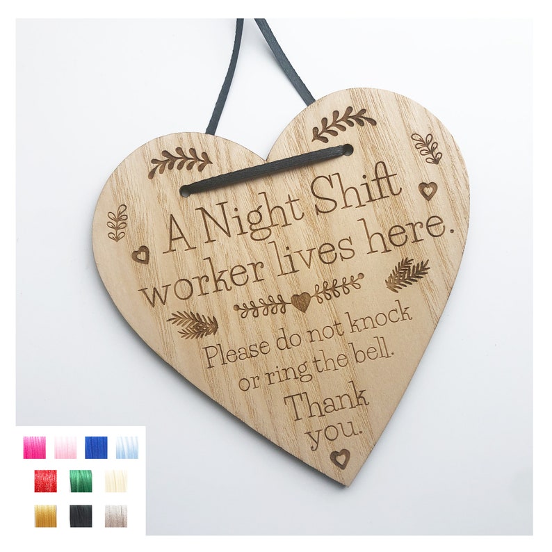 May include: A wooden heart-shaped sign with the text "A Night Shift worker lives here. Please do not knock or ring the bell. Thank you." The sign has a black ribbon for hanging.
