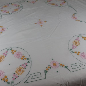 May include: White tablecloth with embroidered floral designs in pink, yellow, and green. The design features a repeating pattern of circles with flowers around the edges.