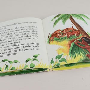 May include: An open book with illustrations. The right-hand page depicts a boy hiding under a leaf, with tigers and a palm tree. The left page contains text. The book has a yellow border.