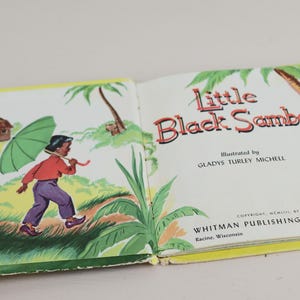 May include: Open book titled "Little Black Sambo" with illustrations. The left page shows a child with an umbrella, the right page has text and a tiger illustration. Published by Whitman Publishing Company.