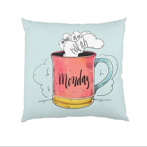 Puede incluir: Una almohada de color azul claro con una ilustración de dibujos animados de una taza de café roja con un borde amarillo. La taza tiene vapor saliendo de ella con las palabras "What? Oh no!  Hel-eh" escritas en el vapor. La taza dice "Monday" en el lateral.