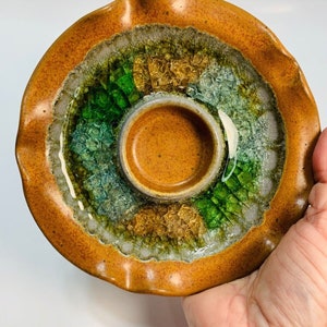 May include: A brown ceramic dish with a scalloped edge and a center ring. The dish is decorated with green and gold crackle glaze.