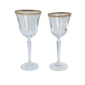 May include: Two clear glass wine glasses with gold rims. The glasses have a tall, slender stem and a round bowl.