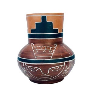 May include: A terracotta vase with a rounded body and a cylindrical neck. The surface features dark brown and black bands, with white etched geometric patterns including a stepped design on the neck and a stylized face motif on the lower body.