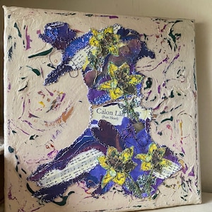 May include: A mixed media artwork depicting the shape of Wales in purple and blue, embellished with yellow flowers and sheet music. The canvas has a textured, off-white background with colorful paint splatters. The text "Calon Lân (Pure Heart)" is visible.