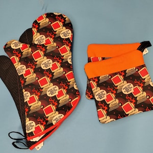 May include: Oven mitts and pot holders with a repeating pattern of retro computers, flames, and the text "HOPE THIS EMAIL FIRES YOU WELL!". The mitts have a black textured grip and the pot holders have orange tops.