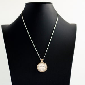 May include: Silver necklace with a round pendant featuring a quote about the earth. The quote reads "For everything that is, is earth, and earth is in everything.  The earth is the mother of all things.  The earth is the source of all things.  The earth is the end of all things.  The earth is the beginning of all things.  The earth is the center of all things."