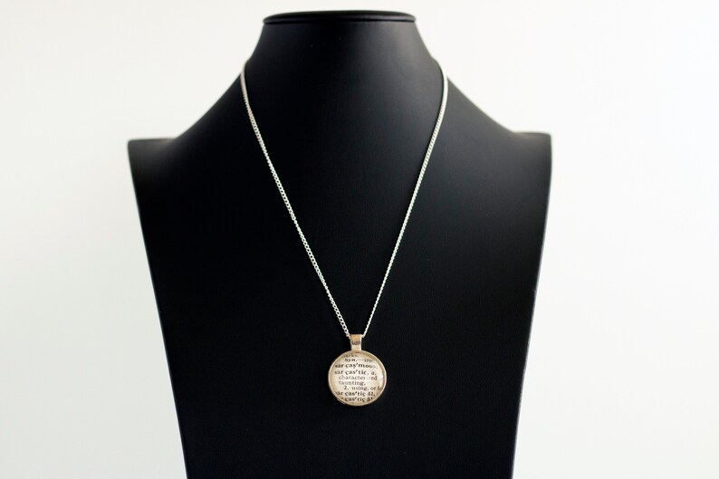 May include: Silver necklace with a round pendant featuring a quote about the earth. The quote reads "For everything that is, is earth, and earth is in everything.  The earth is the mother of all things.  The earth is the source of all things.  The earth is the end of all things.  The earth is the beginning of all things.  The earth is the center of all things."