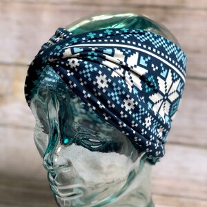 Puede incluir: Una diadema azul y blanca con un diseño de copo de nieve. La diadema está hecha de un tejido suave y elástico, ideal para mantener el cabello fuera de la cara.