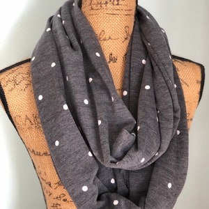 May include: A gray infinity scarf with white polka dots. The scarf is made of a soft, stretchy fabric and is perfect for adding a touch of style to any outfit.