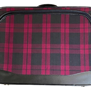 May include: A black and red plaid suitcase with a black leather trim and a gold lock.