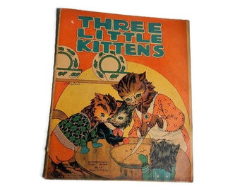 May include: A vintage children's book cover with an orange background and the title "Three Little Kittens". The cover features three kittens, one with glasses, wearing colorful clothing and preparing a pie.